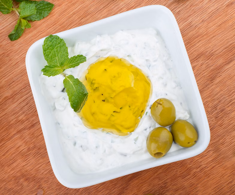 Close-up of flavorful tzatziki topped with olive oil and mint leaves, perfect for Mediterranean cuisine.